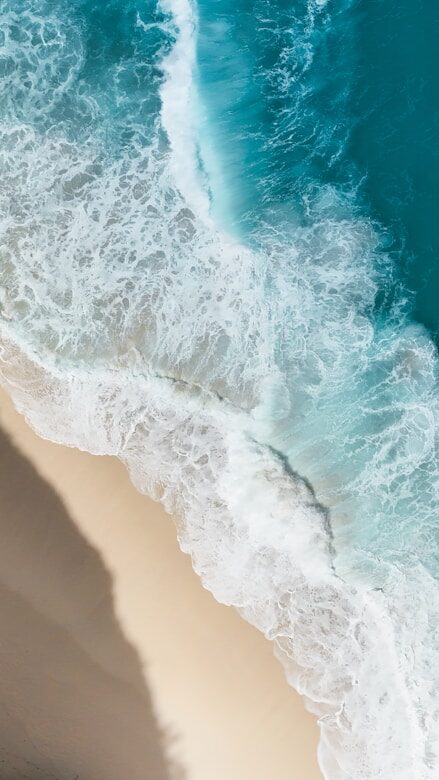 Aerial view of ocean waves crashing on a sandy beach